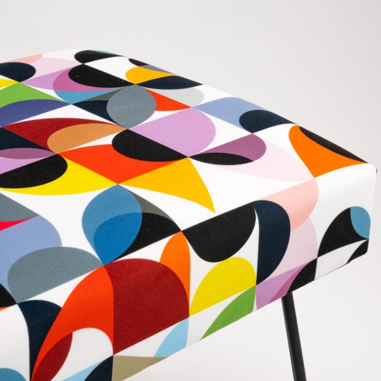 Tapicerowana ławka z kolorowymi wzorami i nogami w kształcie pinów