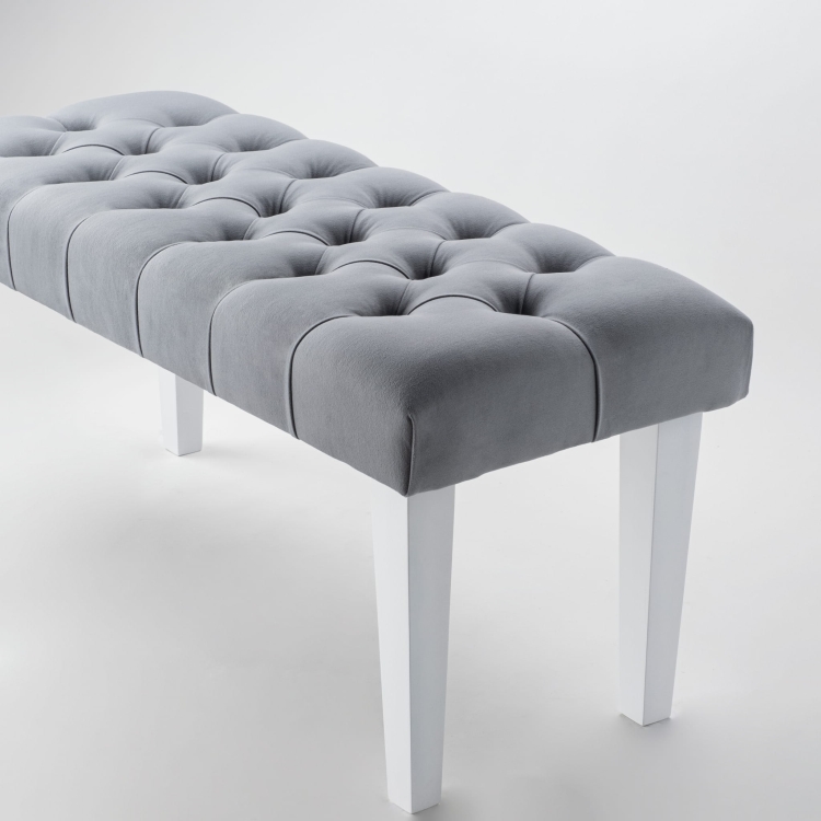 Stylowa ławka w kolorze szarym z pikowaną tapicerką i białymi nogami