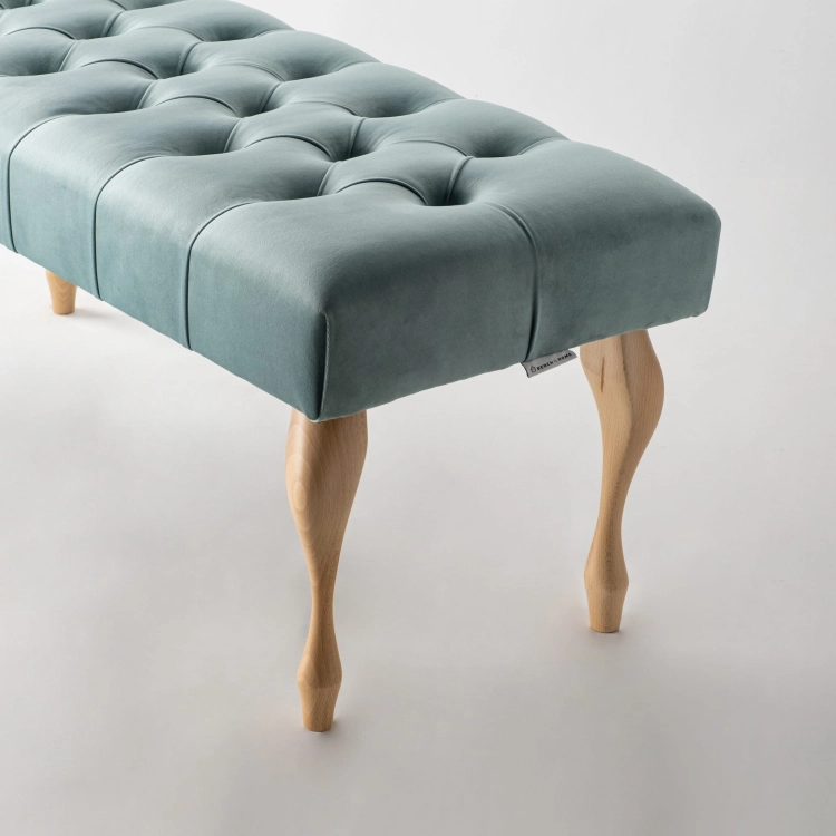 Pikowana ławka w kolorze miętowym z klasycznymi drewnianymi nogami